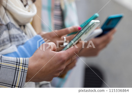 A group of people engaging in social media activities via smartphones in a modern urban setting 115336864