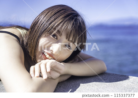 A young woman lying on a breakwater and enjoying the sea A young woman lying on a breakwater and enjoying the sea 115337377