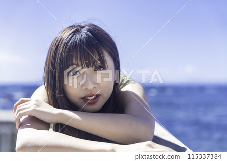 A young woman lying on a breakwater and enjoying the sea A young woman lying on a breakwater and enjoying the sea 115337384
