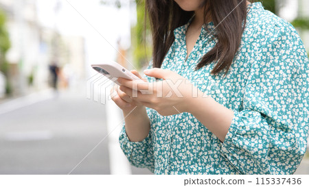 Young woman using a smartphone on the street 115337436