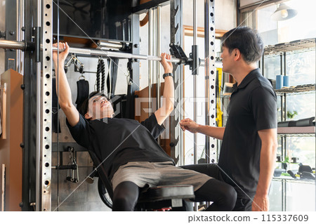 一名男子在健身房接受個人訓練，一名男子擔任訓練師/教練 115337609