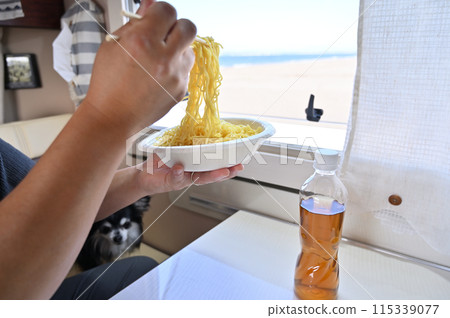 A man eating Zaru Ramen while looking at the sea from a camper van 115339077