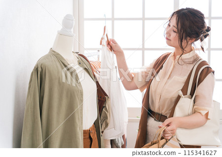 年輕的亞洲女性在服飾店/服飾店挑選衣服 年輕的亞洲女性在服飾店/服飾店挑選衣服 115341627