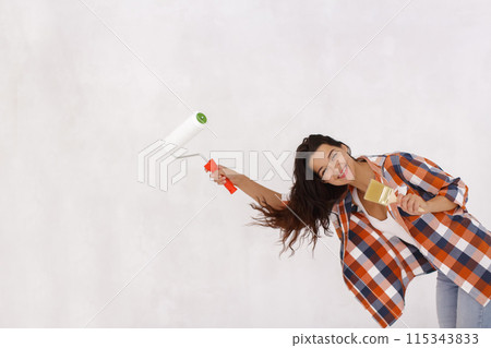 Smiling Woman with Paint Roller and Brush During Fun Home Renovation Smiling Woman with Paint Roller and Brush During Fun Home Renovation 115343833