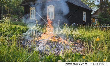 Burning branches outside the village house in eastern europe. 115344895