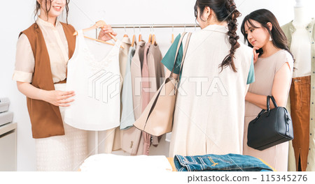 A female sales clerk recommending products at an apparel shop and a female customer who dislikes being served 115345276