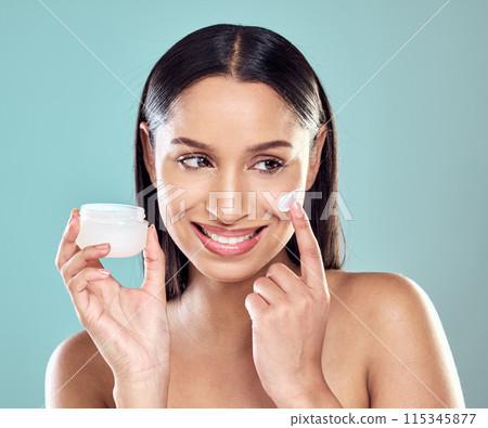 Woman, lotion and apply jar of spf in studio, hydration and cleaning or skincare on blue background. Female person, beauty and cream for facial treatment in container, pamper routine and sunscreen 115345877
