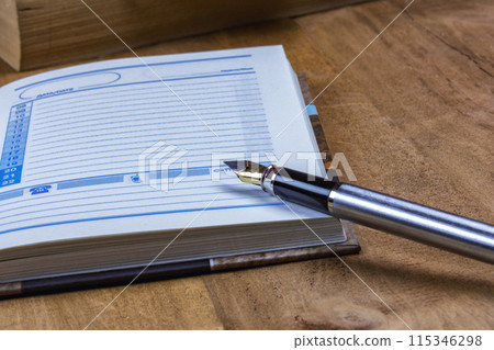 On the open diary page is the fountain pen On the open diary page is the fountain pen 115346298