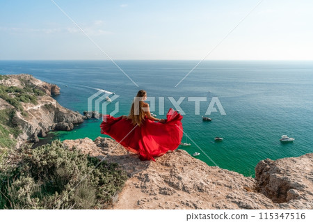 Woman sea red dress yachts. A beautiful woman in a red dress poses on a cliff overlooking the sea on a sunny day. Boats and yachts dot the background. Woman sea red dress yachts. A beautiful woman in a red dress poses on a cliff overlooking the sea on a sunny day. Boats and yachts dot the background. 115347516