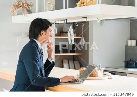 穿著西裝的年輕亞洲商人在家餐桌工作 115347949