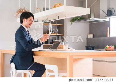 Young Asian businessman in a suit working at his dining table at home 115347951