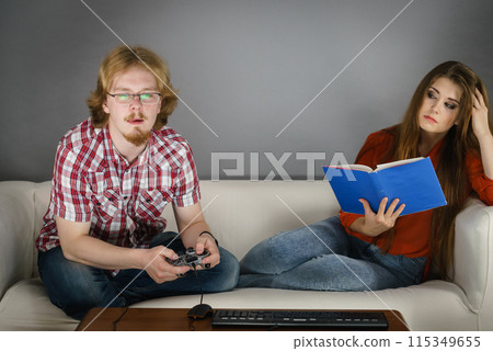 Woman playing games man reading book 115349655