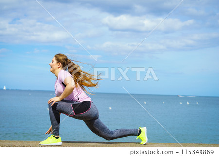 Woman stretching legs next to sea 115349869