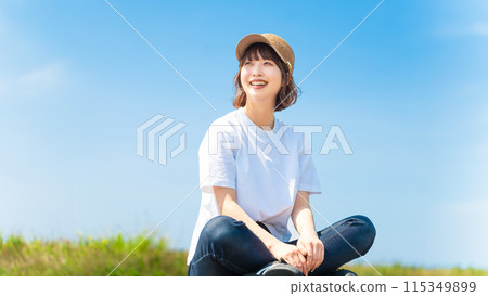 Smiling woman sitting wearing a straw cap 115349899
