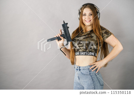 Woman wearing headphones holding gun Woman wearing headphones holding gun 115350118