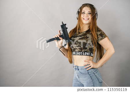 Woman wearing headphones holding gun Woman wearing headphones holding gun 115350119