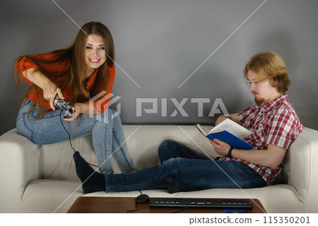 Woman playing games man reading book Woman playing games man reading book 115350201