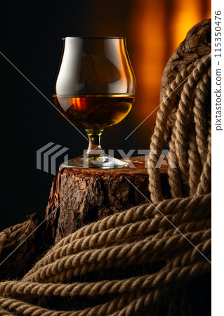 Brandy snifter and rope on a old stumb. 115350476