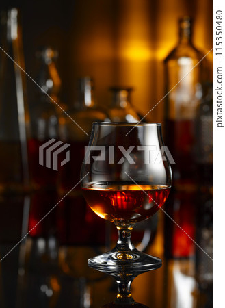 Snifter of brandy on a black table in bar. Snifter of brandy on a black table in bar. 115350480