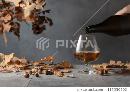 Brandy is poured from a bottle into a glass. 115350502