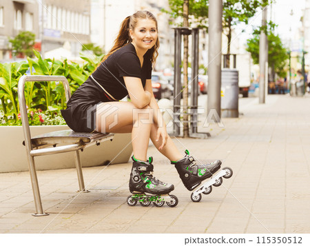Young woman sitting wearing roller skates 115350512
