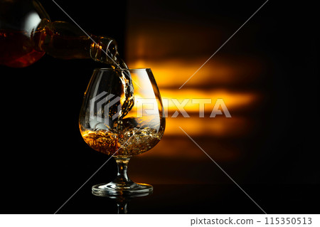 Pouring brandy from a bottle into a snifter. 115350513