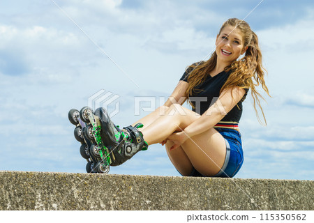Happy young woman wearing roller skates Happy young woman wearing roller skates 115350562