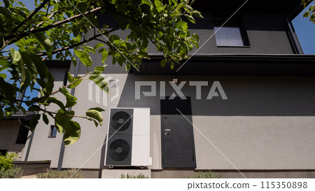 A modern cottage's wall accommodates the outdoor unit of a heat pump. A modern cottage's wall accommodates the outdoor unit of a heat pump. 115350898