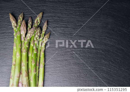 Asparagus. Fresh green asparagus on black slate background. Top view copy space. Asparagus. Fresh green asparagus on black slate background. Top view copy space. 115351295