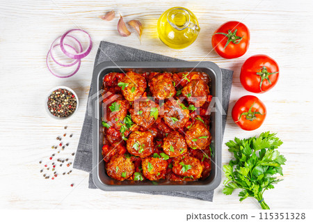 Homemade meatballs with tomato sauce and spices served in black pan on black slate background Homemade meatballs with tomato sauce and spices served in black pan on black slate background 115351328