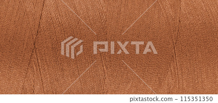 Texture of orange color threads in spool close up, macro. Wide banner, header 115351350