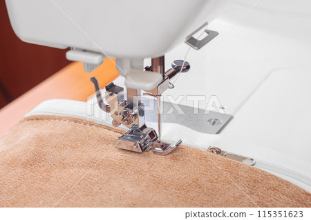 Modern sewing machine special presser foot with beige fabric and zipper, closeup Modern sewing machine special presser foot with beige fabric and zipper, closeup 115351623