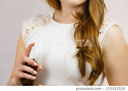 Woman applying hair cosmetic Woman applying hair cosmetic 115352520