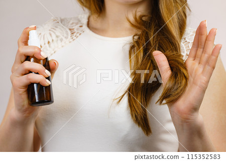 Woman applying hair cosmetic Woman applying hair cosmetic 115352583