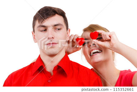 Serious man and crazy woman holds red hearts over eyes Serious man and crazy woman holds red hearts over eyes 115352661