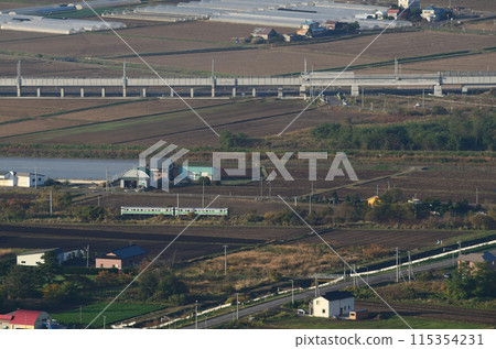 A Kiha 40 series local train on the Hakodate Main Line runs leisurely with the Hokkaido Shinkansen viaduct in the background. A Kiha 40 series local train on the Hakodate Main Line runs leisurely with the Hokkaido Shinkansen viaduct in the background. 115354231