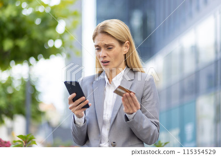 Worried businesswoman standing outdoors, holding a smartphone and credit card, expressing concern and anxiety about financial fraud or online banking issues. Worried businesswoman standing outdoors, holding a smartphone and credit card, expressing concern and anxiety about financial fraud or online banking issues. 115354529