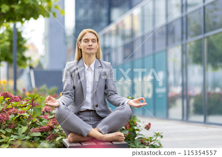 Professional businesswoman practicing yoga and meditation outdoors in the city to relieve stress and improve focus. 115354557
