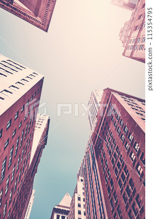 Looking up at New York City skyscrapers against the sun, color toning applied, USA. 115354795