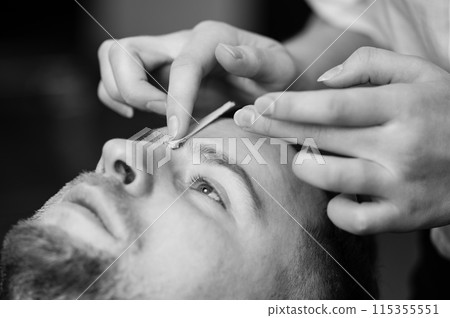 Hair removal procedure in a barbershop. Eyebrows hair wax removal. 115355551