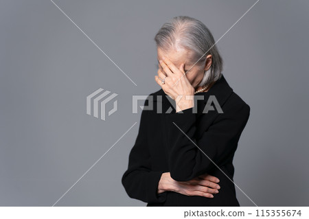 Senior woman in mourning clothes covering her face 115355674