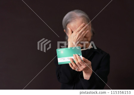 Senior woman in mourning clothes laments as she looks at her bankbook 115356153