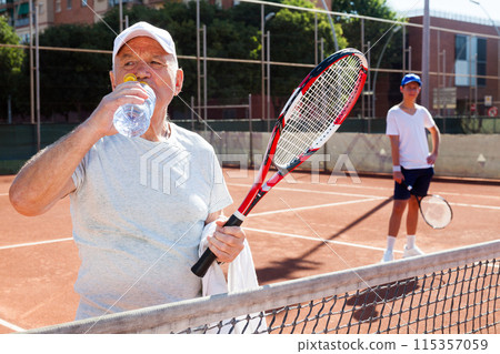 Tennis player drink water on tennis court Tennis player drink water on tennis court 115357059