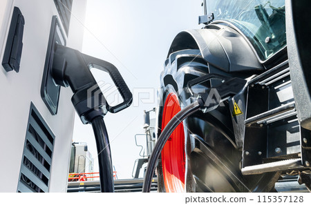 Electric vehicles charging station on a background of agricultural tractor. Concept Electric vehicles charging station on a background of agricultural tractor. Concept 115357128
