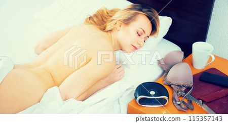 Girl sleeping not covered on bed 115357143