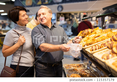Couple chooses sweet puffs in bakery Couple chooses sweet puffs in bakery 115357179