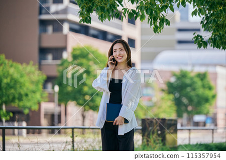 年輕女子一邊走路一邊用智慧型手機打電話 115357954