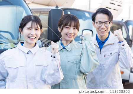 Three truck drivers, both male and female, wearing work clothes and posing with fist pumps Three truck drivers, both male and female, wearing work clothes and posing with fist pumps 115358203