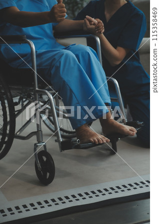 Doctor giving hope. Close up shot of young female physician leaning forward to smiling elderly lady patient holding her hand in palms. Woman caretaker in white coat supporting encouraging old person 115358469