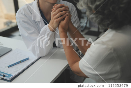 African female doctor hold hand of caucasian woman patient give comfort, express health care sympathy, medical help trust support encourage reassure infertile patient at medical visit, closeup view. 115358479